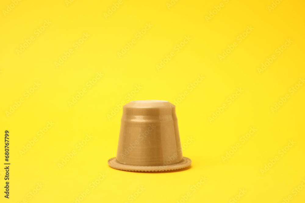 One plastic coffee capsule on yellow background One plastic coffee capsule on yellow background