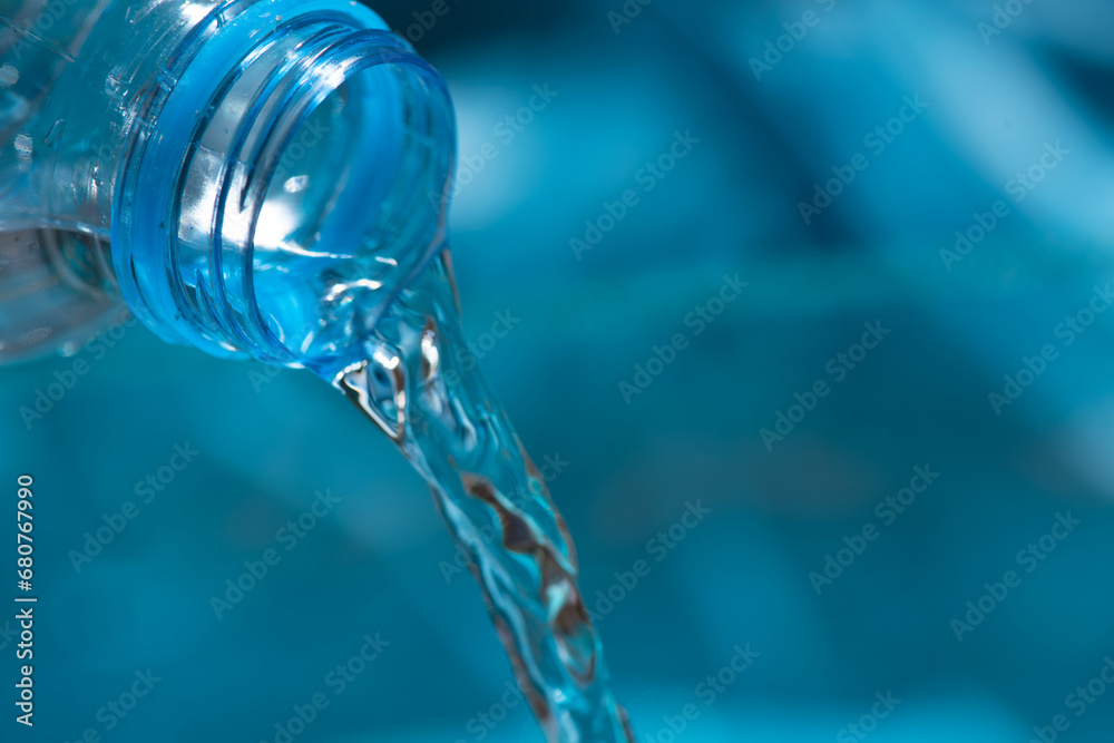 water flowing from a bottle. water pouring into the glass. Pouring water from bottle into glass on blue background. water flowing from a bottle. water pouring into the glass. Pouring water from bottle into glass on blue background.