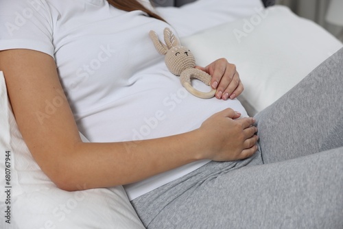 Pregnant woman with bunny toy lying on bed, closeup