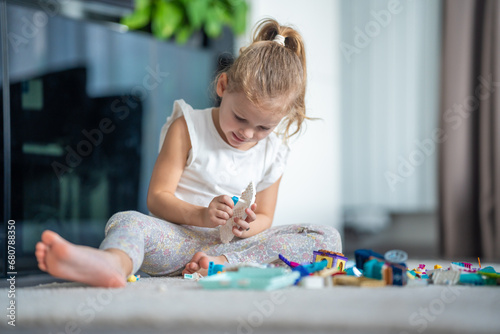 Smiling Little girl playing with small constructor toy on floor in home, educational game, spending leisure activities time concept