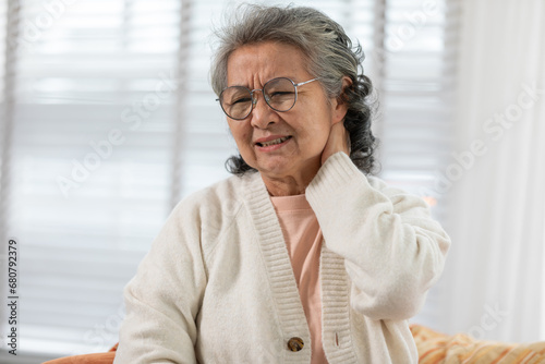 Asian Elderly senior woman with white hairs neck and shoulder pain and illness on sofa alone at home,Elderly Care and insurance Concept