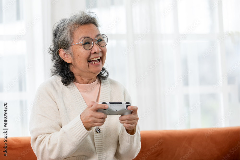 Delighted senior Asian woman immersed in joyful gaming experience at home, showcasing the positive impact of technology on her happiness. Elderly Recreation Concept Delighted senior Asian woman immersed in joyful gaming experience at home, showcasing the positive impact of technology on her happiness. Elderly Recreation Concept