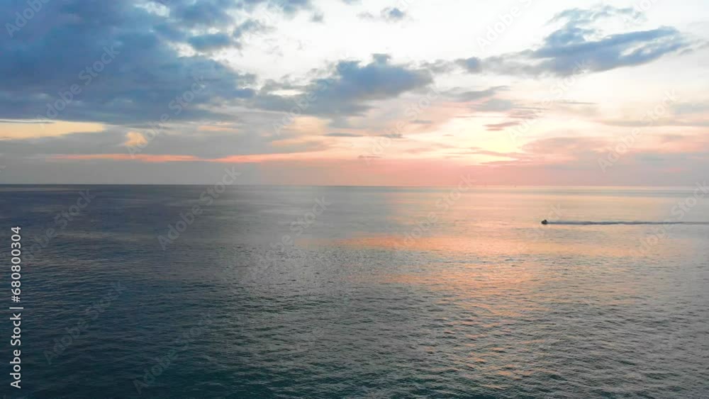 Strafing aerial drone shot of a beautiful sunset across the Andaman Sea horizon, with a jetski passing by located at the tip of Phuket in Southern Thailand. Strafing aerial drone shot of a beautiful sunset across the Andaman Sea horizon, with a jetski passing by located at the tip of Phuket in Southern Thailand.