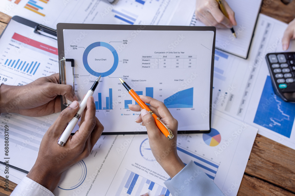 Group of confident business people point to graphs and charts to analyze market data, balance sheet, account, net profit to plan new sales strategies to increase production capacity. Group of confident business people point to graphs and charts to analyze market data, balance sheet, account, net profit to plan new sales strategies to increase production capacity.