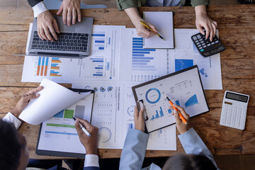 Group of confident business people point to graphs and charts to analyze market data, balance sheet, account, net profit to plan new sales strategies to increase production capacity.	