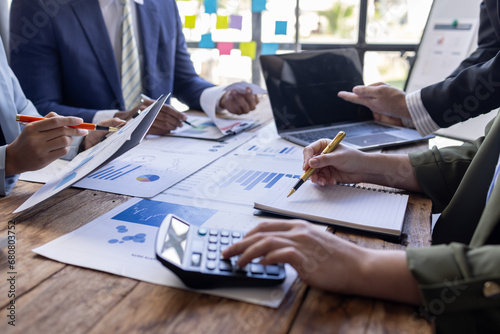 Group of confident business people point to graphs and charts to analyze market data, balance sheet, account, net profit to plan new sales strategies to increase production capacity. 