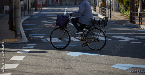 冬の朝の住宅街の横断歩道を渡る一人の自転車を乗っている女性の姿