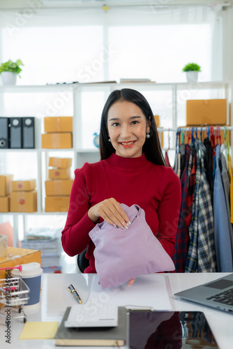 Asian female entrepreneur SME business owner works with laptop, box and phone to shop online at home. Online Marketing SME Ecommerce Online Packaging Delivery