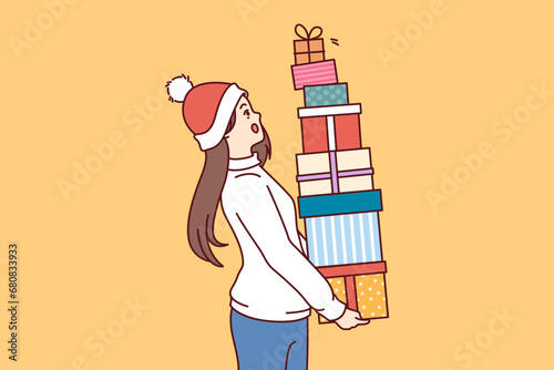 Woman with bunch of christmas gifts in hands is in shock and is afraid to drop boxes presented by santa claus for new year. Surprised girl holding gifts received for participating in christmas sale
