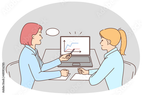 Businesswomen discuss financial graphs in office