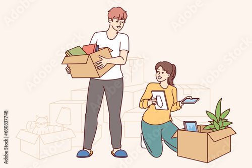 Happy couple moves into new apartment, unpacking boxes personal belongings and rejoicing at improved home conditions. Cheerful guy and girl took out mortgage to buy house and moves to prosperous area