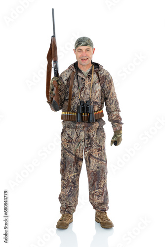 Full lengt portrait of happy duck hunter with a rifle and binoculars say YES and looks at something below his feet, isolated on white background. Fifty-year-old man in hunting uniform posing in studio