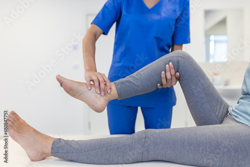 close up of female physiotherapist is helping senior elder woman stretching her hamstring and doing thigh or leg rehabilitation in exercise room - she is lying on massage bed photo