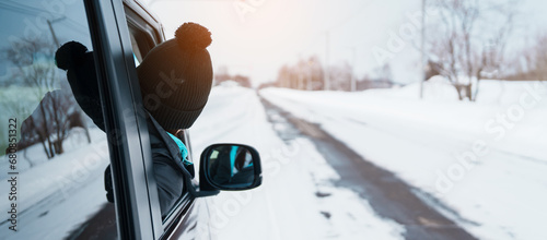 Happy Traveler driving car on snowy road, woman Tourist enjoying snow forest view from the car window in winter season. Winter travel, Road trip, Exploring and Vacation concepts photo