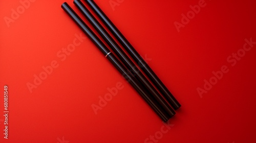 Sleek black chopsticks on a radiant red background.