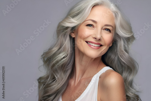 Older and mature woman with smooth skin and beautiful long, grey, flowing hair. Beauty and cosmetics advertising concept image. 
