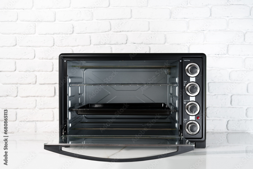 Mini electric oven against white brick wall in the kitchen Mini electric oven against white brick wall in the kitchen