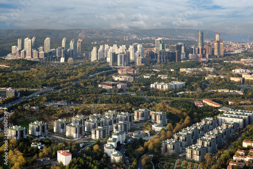 Aerial view to a modern city with skyscrapers, parks and traffic. Against the background of a sunset sky with clouds.