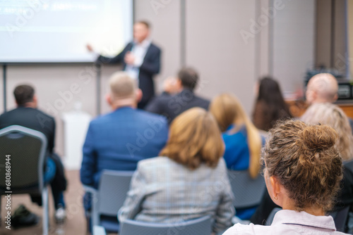 Back view of businesswoman attending presentation with diverse participants in conference hall 