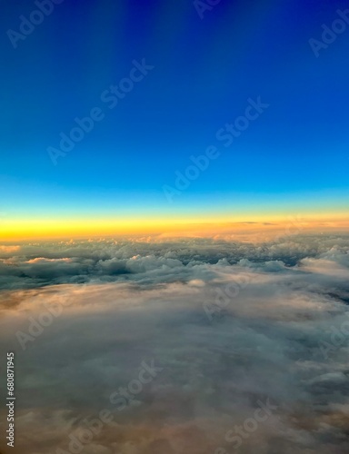 Blick aus dem Flugzeug Fenster über den Wolken mit Sonnenuntergang  © Andrea