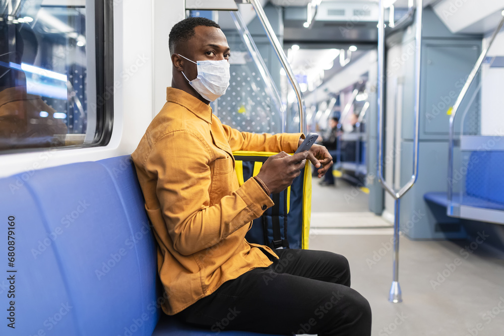 Portrait of a pizza delivery man in a protective mask who rides the subway to deliver an order to a customer during a pandemic