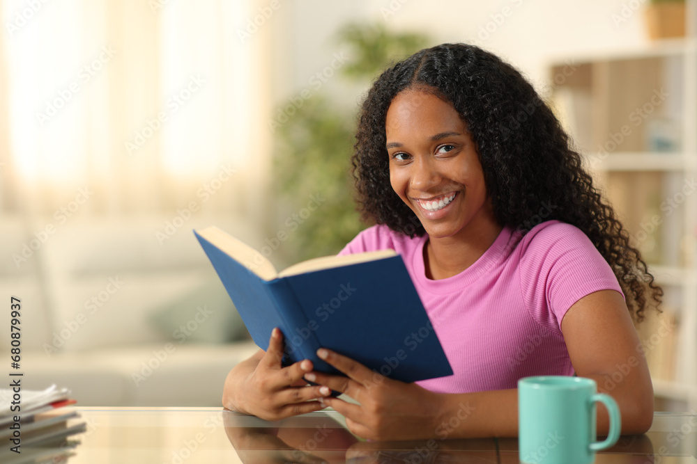 Happy black reader looking at camera holding book Happy black reader looking at camera holding book