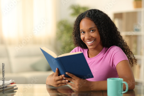 Happy black reader looking at camera holding book photo