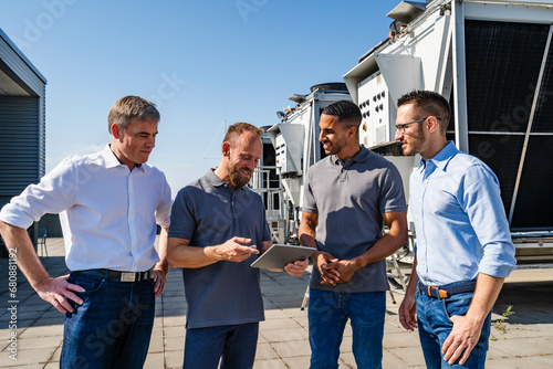 Businessmen and employees having a meeting on rooftop beside refrigeration installation photo