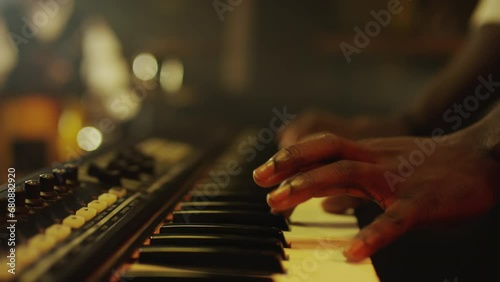 Closeup of unrecognizable African American male hands of jazz musician playing synthesizer on dimmed light stage in night club photo