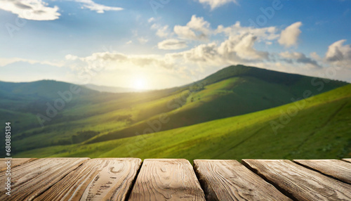 Wooden table in front of blurred green hills with cloudy sky. For product showing