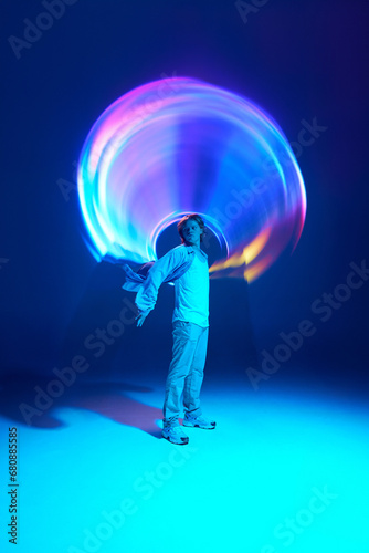 Full-length portrait of attractive young man posing in vivid blue neon light illuminating futuristic, digital projector reflection photo