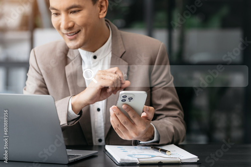 Businessman sitting at table using mobile phone, online working on laptop, searching the information on internet network.