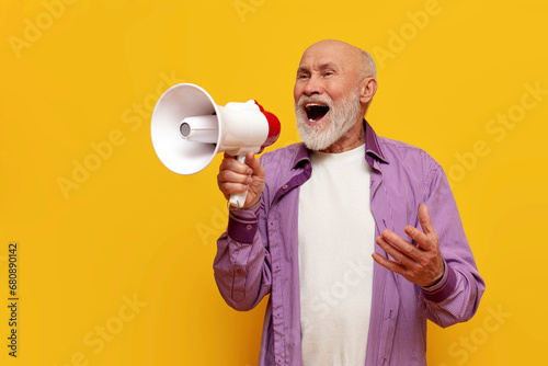 old bald grandfather in purple shirt announces information into megaphone on yellow isolated background