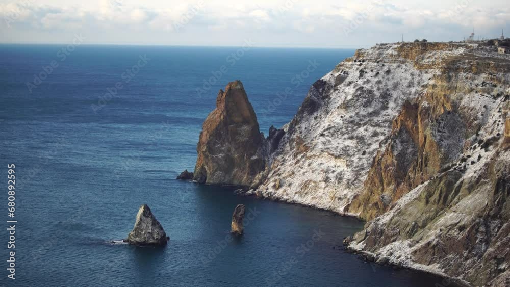 Snow covered rocky cliffs over sea. Winter landscape over the sea bay. Juniper tree under snow. Concept of winter holidays, travel and recreation. Cape Fiolent in Balaklava, Sevastopol, Crimea Snow covered rocky cliffs over sea. Winter landscape over the sea bay. Juniper tree under snow. Concept of winter holidays, travel and recreation. Cape Fiolent in Balaklava, Sevastopol, Crimea