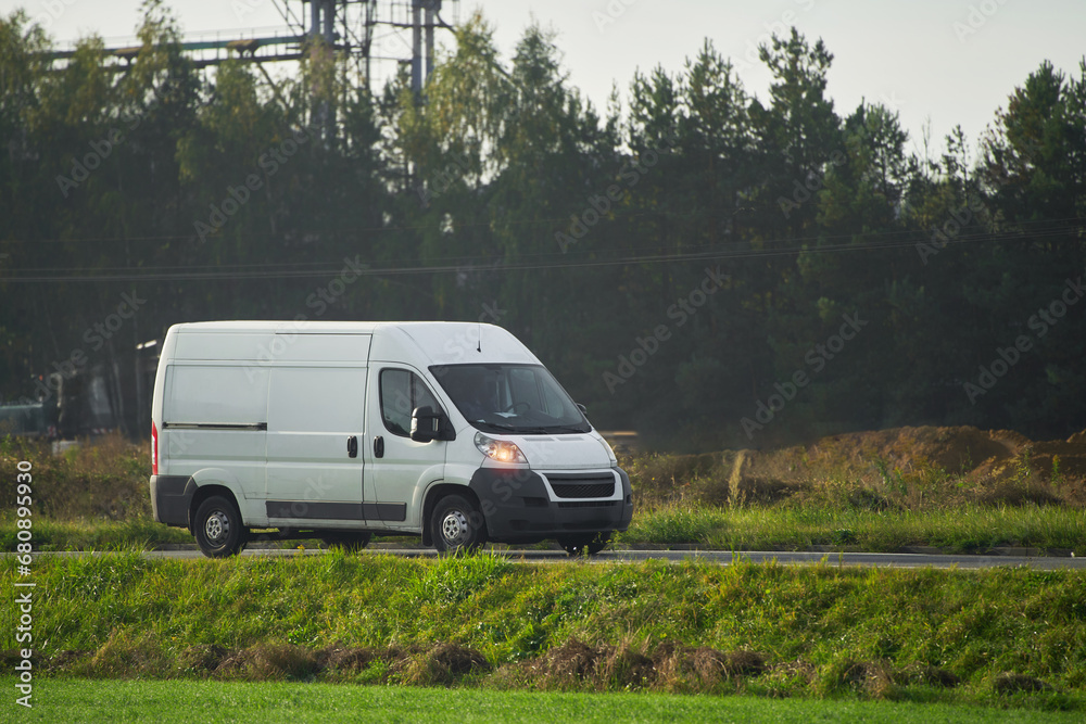 A white van on the road, shipping cargo and packages from the warehouse to the customers, showing the design and branding of their logistics service. A white van on the road, shipping cargo and packages from the warehouse to the customers, showing the design and branding of their logistics service.