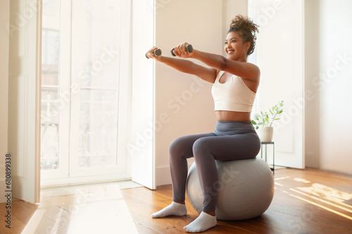 lady performs arm workout holding dumbbells using balance ball indoor photo
