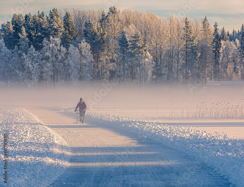 Man walking in snow by forest at sunrise photo