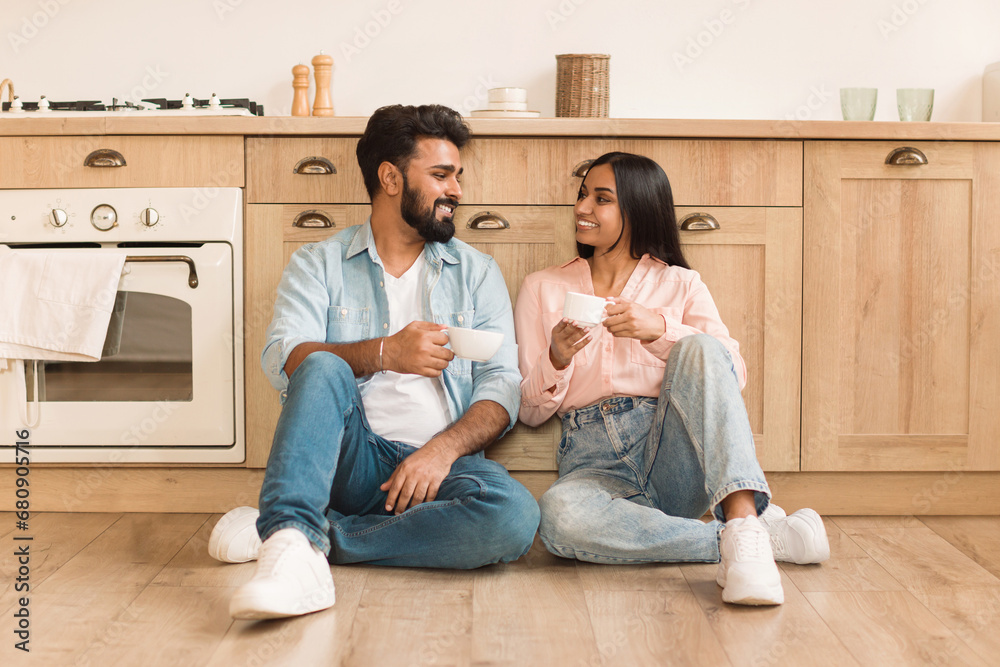 Happy indian couple chatting over coffee in kitchen Happy indian couple chatting over coffee in kitchen