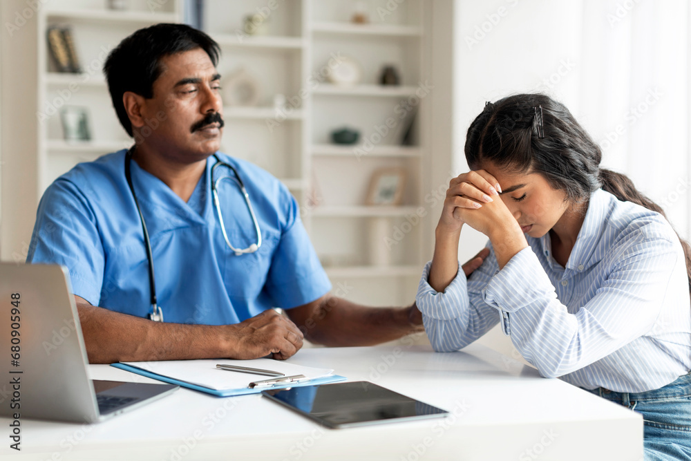 Fototapeta premium Indian Therapist Man Comforting Upset Female Patient During Meeting In Clinic