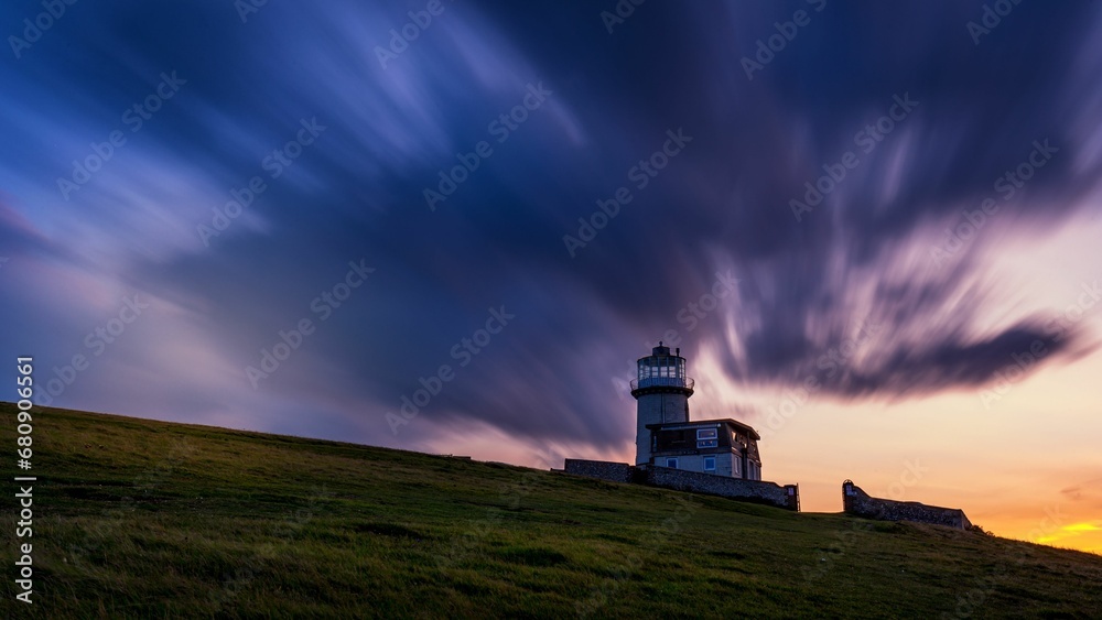 Stunning view of the Bele Tout Lighthouse illuminated in front of a vivid and dramatic sunset