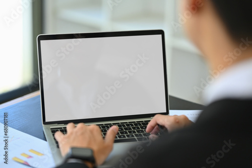 Over shoulder view of male financier using laptop at office desk