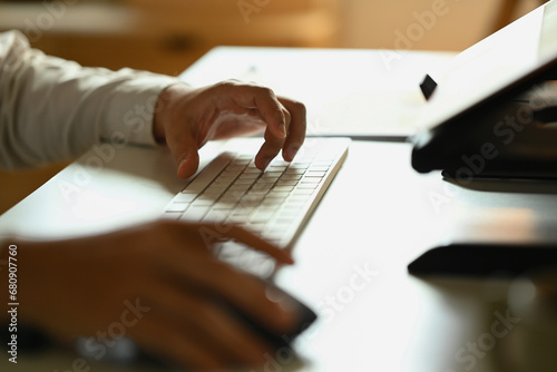 Closeup businessman hands typing on keyboard, searching information or browsing internet at desk