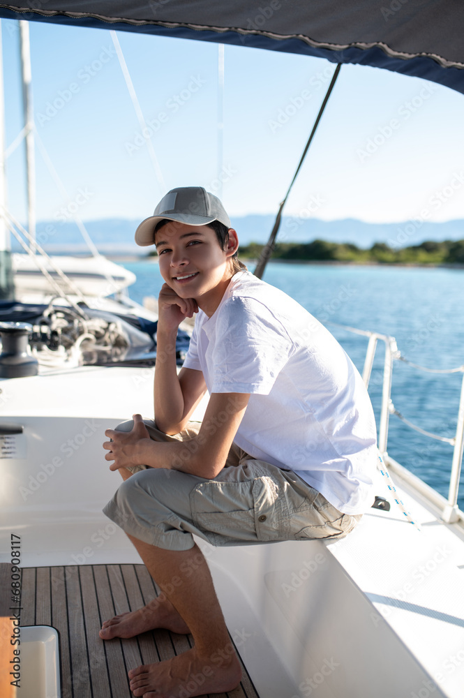 Teen in white tshirt on yacht looking contented