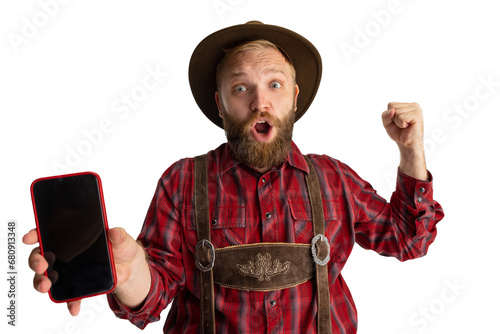 Wow, surprised. Young bearded man, waiter in traditional Bavarian costume using phone isolated over transparent background. Celebration, oktoberfest, festival concept. photo