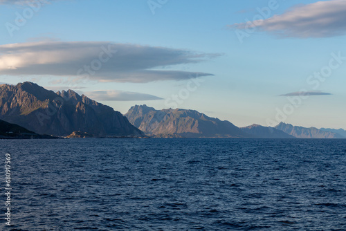 Green mountains range with the sea on the shore and clouds in the sky
