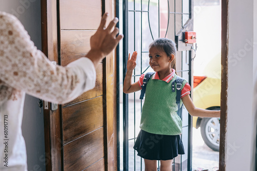 School girl with backpack waving goodbye to her parent before going to school photo