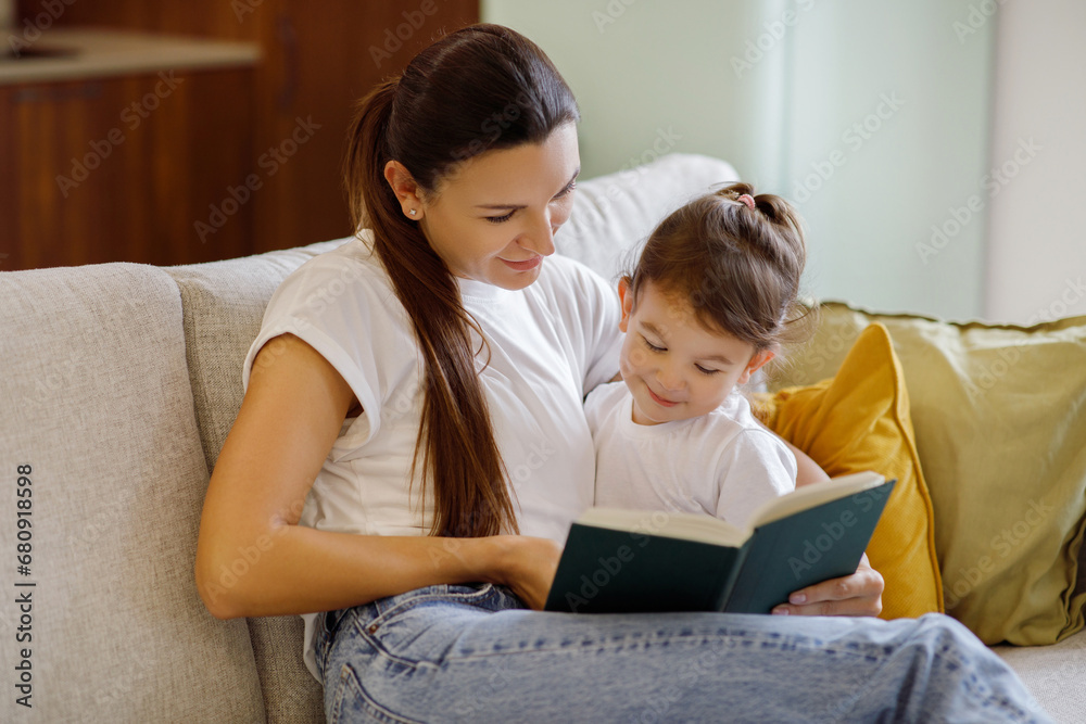 Baby Development. Mother Reading Book With Her Cute Toddler Daughter At Home Baby Development. Mother Reading Book With Her Cute Toddler Daughter At Home