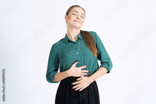 Attractive young woman touches her stomach after a delicious meal isolated on a white studio background. The girl is pregnant, she is an expectant mother. Pregnancy, motherhood