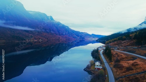 Aerial Landscape of Mountainous Fjord, Flowing Waterfall, and Forest Covered in Clouds, Capturing Natural Serenity