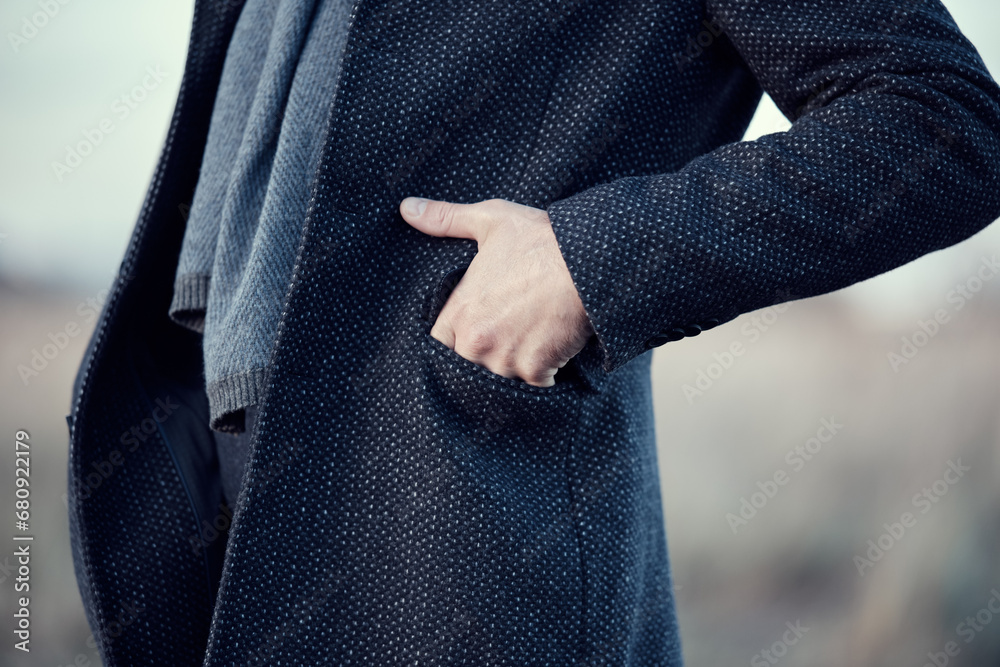 Man in a navy blue coat and a blue wool scarf, hand in pocket. Warm classic autumn winter men's clothing